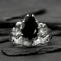 a close up of a ring with a black stone in the center on a rock