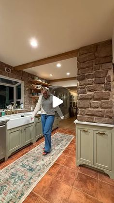 a woman is walking through the kitchen in front of an open sink and stove top