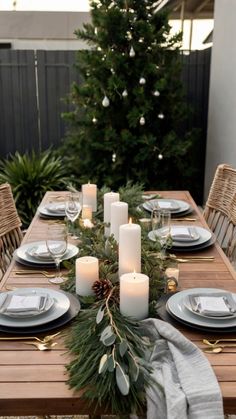 a table set with candles, plates and napkins for christmas dinner on an outdoor patio