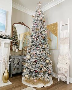 a white christmas tree in a living room with gold and silver ornaments on the top