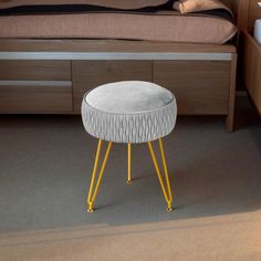 a white stool with yellow legs in front of a bed