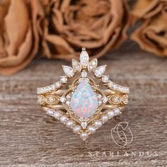 a white opal and diamond ring on a wooden table with roses in the background