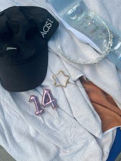 an assortment of personal items laid out on top of a towel, including a hat and earring