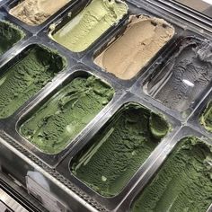 an assortment of ice creams in trays with green and yellow flavors on them