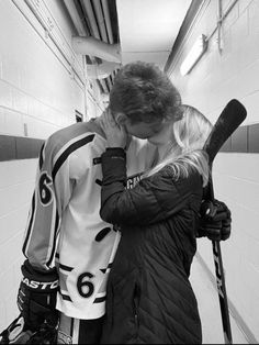 a man and woman are kissing in the locker room with baseball bats on their shoulders