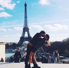 a man and woman kissing in front of the eiffel tower on a sunny day