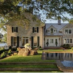 a large house with a pool in front of it and trees around the pond area