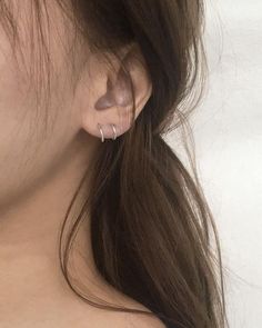 a close up of a woman's ear with two small hoops on it