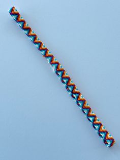 a colorful bracelet on a blue background with an orange and white zigzag pattern