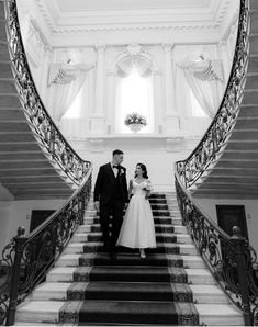 a bride and groom walking down the stairs at their wedding reception in black and white