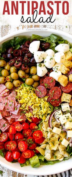 a large salad with olives, tomatoes, and other ingredients in a white bowl