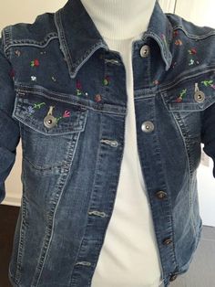 a white mannequin wearing a jean jacket with flowers on it