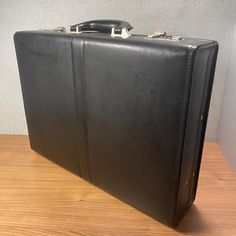 This is a gorgeous retro black briefcase, made by Samsonite with a double combination lock (code is 000, 000)! It has a lovely smooth texture, with decorative belt down the center of the front and back on the exterior.  Black interior with two rigid accordion-style pockets. a couple of pen pocket holders, a zipper pocket, and a calculator or phone holder. All the finishing pieces satin nickel colored metal, including the snap lock and handle brackets.  Great to gift to the professional in your l Classic Black Rectangular Case, Classic Briefcase With Hasp Closure For Travel, Classic Travel Briefcase With Hasp Closure, Elegant Black Rectangular Briefcase, Formal Black Rectangular Case, Classic Business Briefcase With Hasp Closure, Black Rectangular Briefcase With Case, Vintage Rectangular Black Briefcase, Vintage Black Rectangular Briefcase