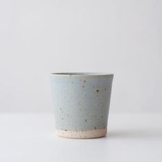 a white and blue cup with speckles on it sitting on a counter top