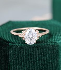 an engagement ring sitting on top of a green velvet box with a diamond in the center