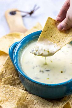 a person dipping tortilla chips into a blue bowl