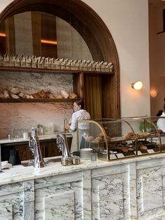 a man standing in front of a counter filled with pastries and desserts at a restaurant