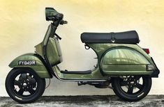 a green scooter parked in front of a wall with the words pxsingapura on it