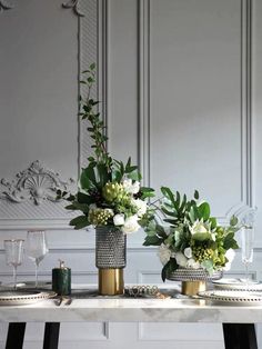 two vases filled with flowers sitting on top of a table next to plates and glasses