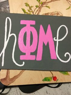 a wooden sign with the word mom painted on it's side next to a pair of scissors