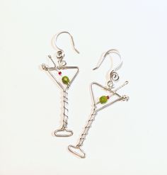 "Fun martini glass earrings ..now with improved more realistic beads for the olive...I used 4mm green faceted oval shape beads.  These also have a better earhook placement in the center so they hang straight not tilted.    The silver wire is 18 gauge silver plated non tarnish.  Drop length is 2.25\".  Your choice of silver or goldplate too. *If ordered as a gift it will come in a box as shown.  Just added a new variation of Espresso martinis! ..with brown bronzite beads and white faux pearls beads.  Now available you can order the necklace.. pendant martini with chain.   Chain is 20\" stainless steel.  Gold chain is goldplate. * I also have many other beverage party earrings too ! : Champagne : https://www.etsy.com/listing/1380883157   Margarita: https://www.etsy.com/listing/1557159350/ Wi Party Glass Jewelry Wire Wrapped, Party Wire Wrapped Glass Jewelry, Wire Wrapped Czech Glass Jewelry For Party, Green Wire Wrapped Jewelry For Party, Wire Wrapped Silver Plated Ring For Party, Funky Earrings Diy, Martini Earrings, Weird Earrings, Espresso Martinis