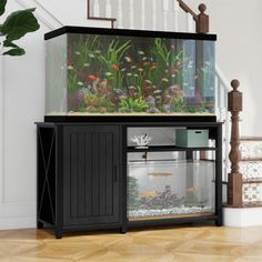 a fish tank sitting on top of a wooden cabinet in front of a stair case