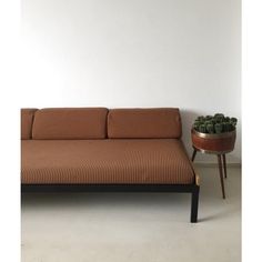 a couch sitting next to a table with a potted plant on top of it