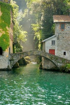 a stone bridge over a river next to buildings