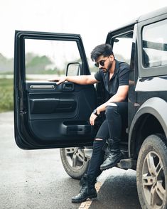 a man sitting in the back of a black truck with his foot on the door