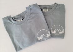 Comfort Colors t-shirts with a super simple embroidered mountain range design. Great shirt for an outdoor adventurer, someone who enjoys nature and loves hiking. Pre shrunk and garment dyed, these shirts get softer as you wash and wear them and last a lifetime! These have a vintage look and a lived in feel! Choose to have the font on the side or center of the t-shirt. Keep in mind, when on the side the font will be smaller and the middle it will be larger. Please make sure when ordering these th Cotton Relaxed Fit Top For Hiking, Relaxed Fit Cotton Top For Hiking, Relaxed Cotton Top For Hiking, Crew Neck Cotton Top For Hiking, Range Design, Mountain Tshirt, Customise T Shirt, Look Vintage, Mountain Range