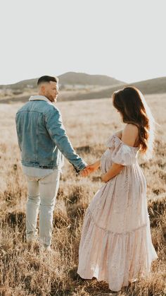 a man and woman holding hands in a field