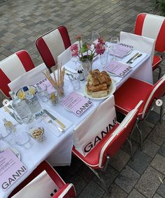 a table set up for a party with pink and white chairs