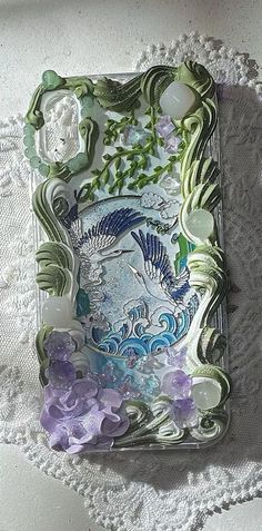 there is a glass plate with flowers and birds on the surface next to doily