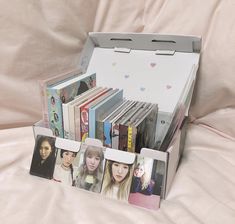 an open box with pictures of people in it on top of a white sheet covered bed