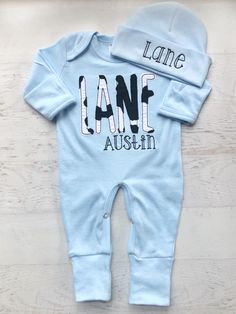 This light blue and cow print baby romper is so sweet for little ones! The black and white cow print, black script middle name, on the soft blue sleeper is so cute for a little farm loving baby! Please leave exact spelling of the childs name. Please double check the spelling as I cannot refund or replace any item for incorrect spelling. Unless otherwise specified, first name name will be in the large appliqué letters, and middle name will be be in the smaller embroidered letters. First name will Customizable Fitted Onesie For Family Matching, Customizable Fitted Onesie For Summer, Cute Fitted Onesie With Custom Print, Fitted Long Sleeve Onesie With Letter Print, Fitted Onesie With Name Print For Summer, Personalized Fitted Cute Onesie, Personalized Fitted Onesie For Spring, Fitted Blue Onesie With Letter Print, Fitted Summer Onesie With Name Print