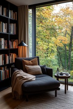 a couch sitting in front of a window next to a book shelf filled with books