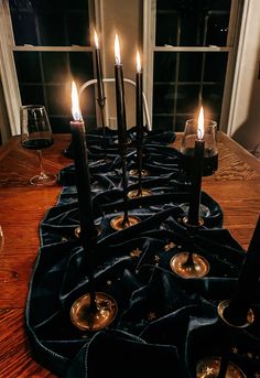 a long table with candles on it and some wine glasses in front of the window