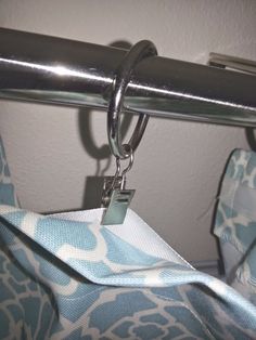 a blue and white patterned curtain with a metal hook hanging from it's side