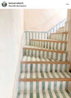 a set of stairs with green and white striped carpet on the bottom, next to a wall