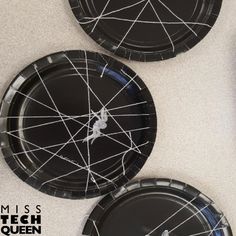 three black paper plates with spider web designs on them