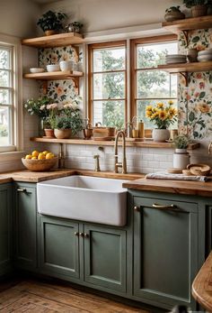 a kitchen with green cabinets and white sink in front of two windows, filled with sunflowers