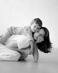 black and white photograph of a woman holding a child on her back while laying on the floor