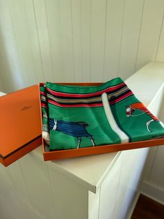 Green and multicolor Hermès 90cm silk scarf with "Couvertures et Tenues De Jour" motif and hand rolled edges. Includes box. Condition: Excellent: Item is clean and shows Hand Roll, Silk Scarf, Conditioner, Silk