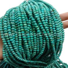 the beads are being held by a person's hand, and they are all turquoise green