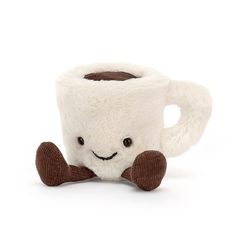 a coffee cup with a smiling face on it's side sitting next to a brown and white dog toy