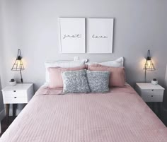 a bed with two lamps on either side of it and pink comforter in the middle