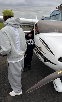 two people standing in front of a small plane