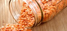 a jar filled with red lentils sitting on top of a wooden table