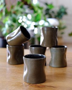 four ceramic cups sitting on top of a wooden table