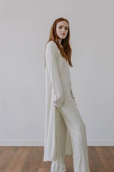 "This luxe, full length lightweight cardigan is made from a finely ribbed fabric with a super soft hand feel. It has a relaxed fit, drop shoulders and slouchy sleeves for a slightly oversized look. Made from 90% plant based, environmentally responsible TENCEL, it's light as air while providing the perfect amount of coverage. The 10% Spandex fabrication also adds a bounce and stretch for exceptional comfort. Like all of our pieces, this cardigan is exclusively handmade to order by us in limited q Wide Legged Jumpsuit, Elegant Pants Suits, Jumpsuit And Cardigan, Long Oversized Cardigan, Cream Colored Cardigan, Luxe Loungewear, Spring Cardigans, Luxury Loungewear, Black Cotton Dresses